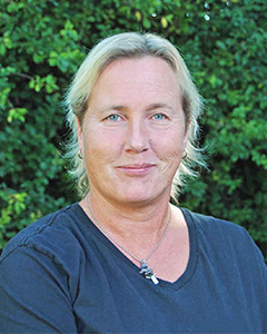 Ansiktsformen är oval. Blond hårfärg. Håret är tillbakakammat. Ler med stängd mun. Ögonen är blåa och triangelformade. Mörkblå tröja.